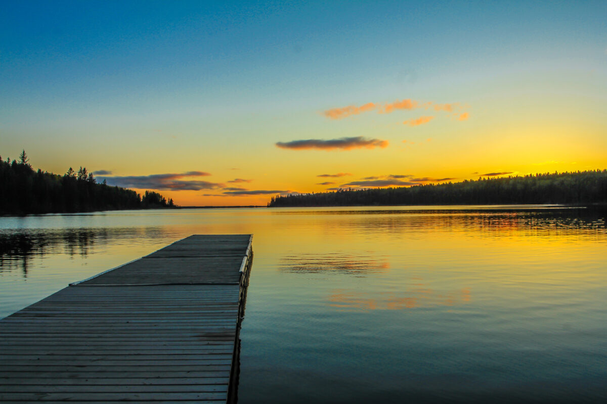 Dock extending into beautiful clear lake, brilliant sunlight over the lake