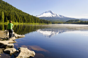 Beautiful Trillium Lake. man fishing on still lake, Mount Hood in the background